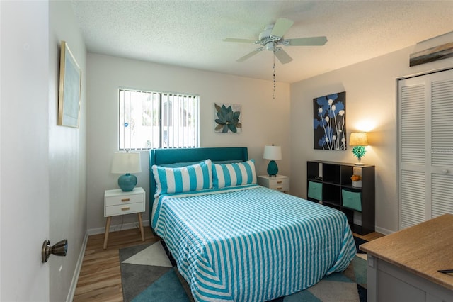 bedroom featuring a closet, baseboards, ceiling fan, a textured ceiling, and wood finished floors
