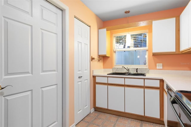 kitchen with white cabinets, decorative light fixtures, range with electric cooktop, a sink, and light countertops