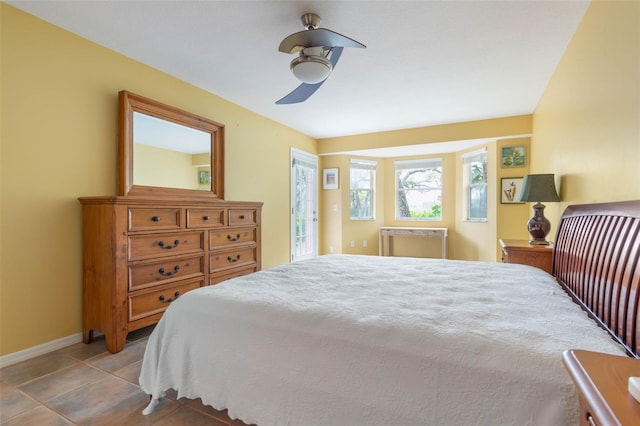 tiled bedroom with ceiling fan and baseboards