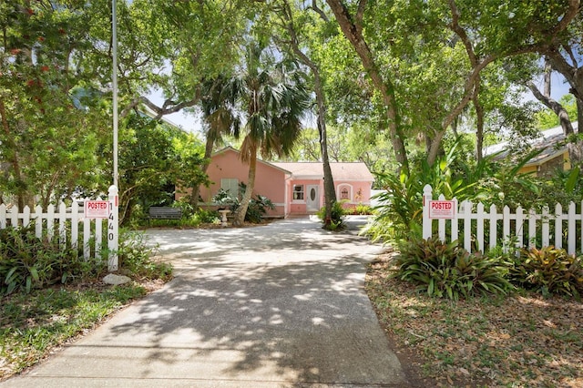 view of front of property with concrete driveway, stucco siding, and fence