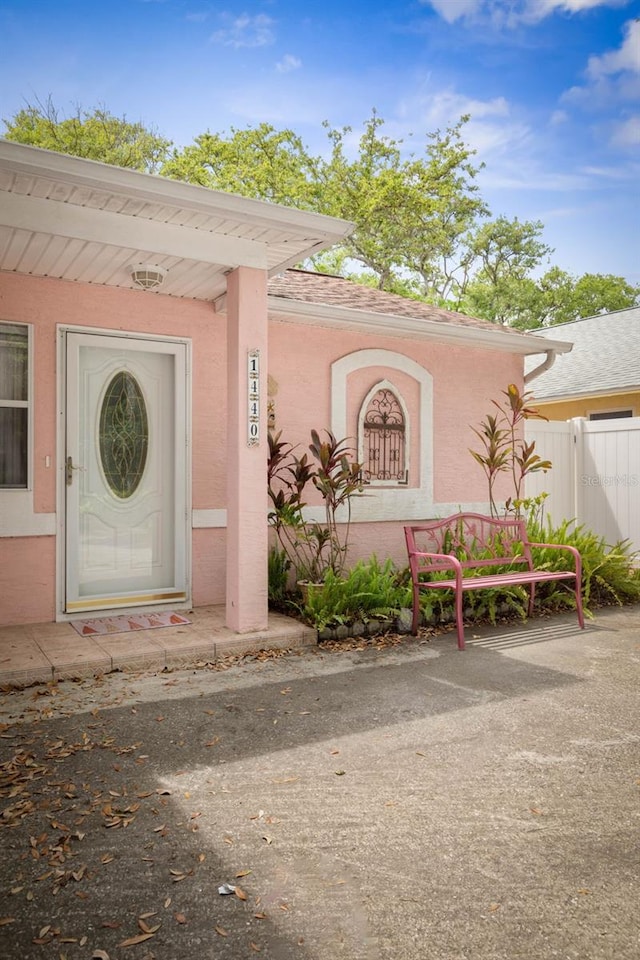 view of exterior entry featuring fence and stucco siding