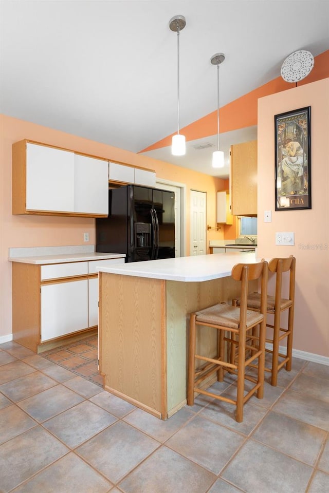kitchen with a peninsula, light countertops, vaulted ceiling, and black fridge with ice dispenser