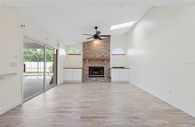 75 Fortune Ln, Palm Coast, FL 32137 - unfurnished living room with a ceiling fan, light wood finished floors, a skylight, a brick fireplace, and high vaulted ceiling