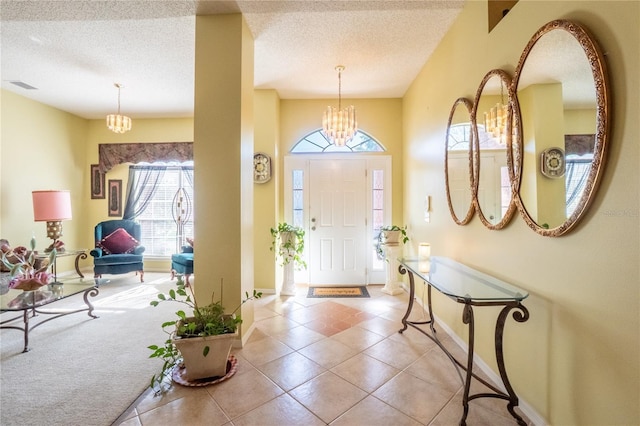 entrance foyer with visible vents, plenty of natural light, a notable chandelier, and tile patterned flooring