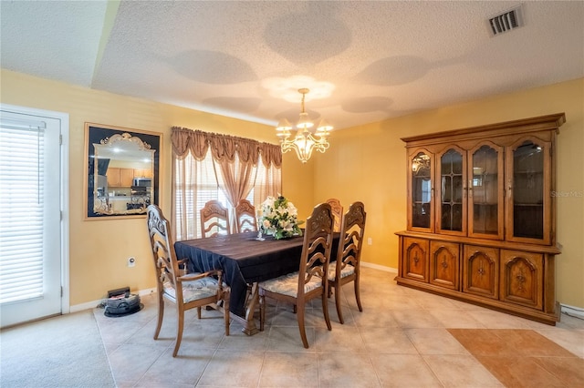 dining space with an inviting chandelier, light tile patterned floors, a textured ceiling, visible vents, and baseboards