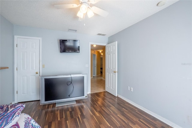 bedroom featuring baseboards, a textured ceiling, visible vents, ceiling fan, and wood finished floors