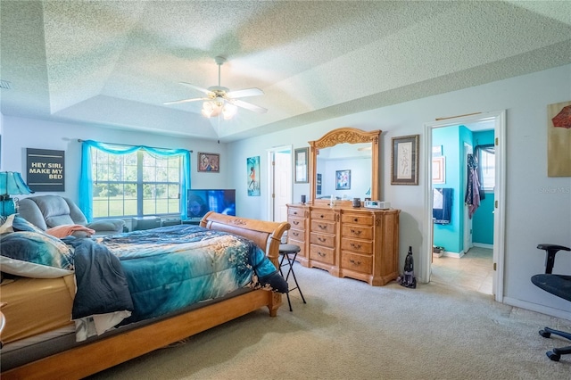 carpeted bedroom featuring a raised ceiling, a textured ceiling, baseboards, and a ceiling fan