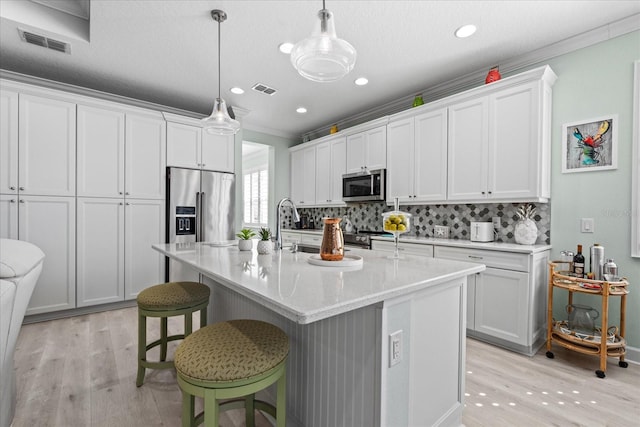 540 Good Life Way, Daytona Beach, FL 32124 - kitchen featuring stainless steel appliances, light wood finished floors, backsplash, a center island with sink, and ornamental molding