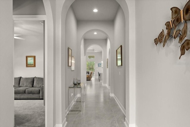 hall featuring recessed lighting, arched walkways, and baseboards