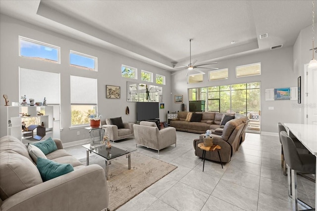 living area featuring visible vents, baseboards, a raised ceiling, and ceiling fan