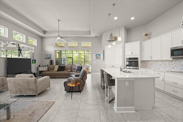 kitchen with a towering ceiling, appliances with stainless steel finishes, a sink, light countertops, and open floor plan