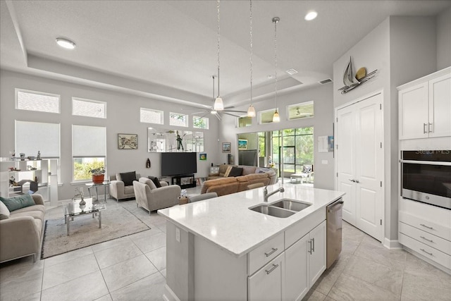kitchen with a ceiling fan, white cabinets, appliances with stainless steel finishes, a sink, and open floor plan