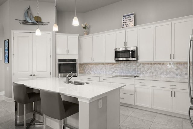 kitchen featuring stainless steel appliances, white cabinetry, a sink, and decorative backsplash
