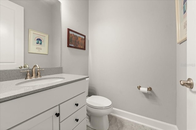bathroom featuring toilet, vanity, and baseboards