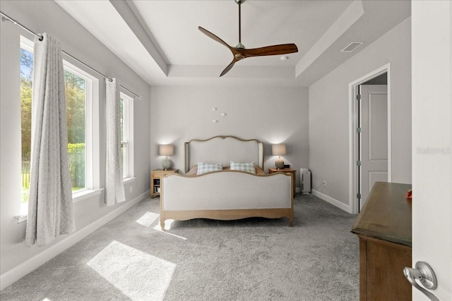 bedroom featuring a tray ceiling, baseboards, carpet flooring, and visible vents