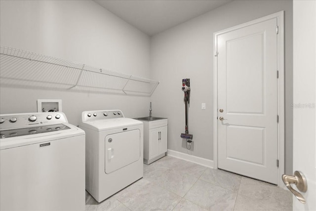 washroom featuring baseboards, washer and clothes dryer, a sink, and cabinet space