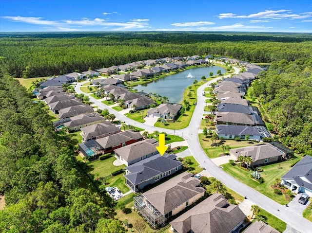 drone / aerial view featuring a wooded view, a residential view, and a water view
