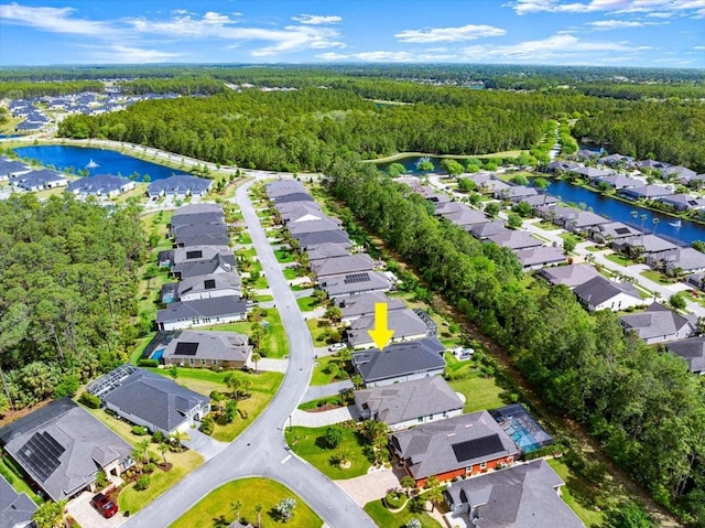 drone / aerial view featuring a water view, a residential view, and a view of trees