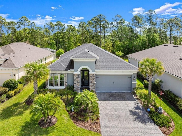 view of front facade with a garage, stucco siding, decorative driveway, and a shingled roof