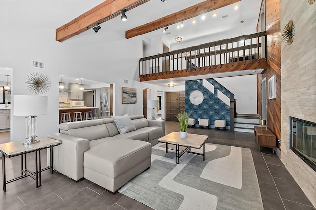 living room with beamed ceiling, a fireplace, dark tile patterned flooring, visible vents, and stairway
