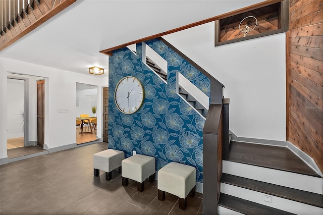 stairs featuring wood walls, an accent wall, and baseboards