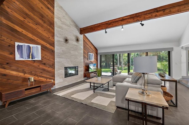 living room featuring wood walls, high vaulted ceiling, track lighting, and a fireplace