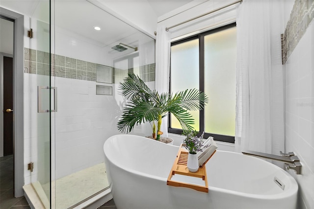 full bathroom featuring a shower stall, a freestanding tub, and tile walls