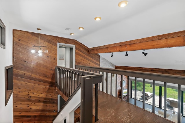 hallway featuring wood walls, an upstairs landing, vaulted ceiling with beams, and wood finished floors