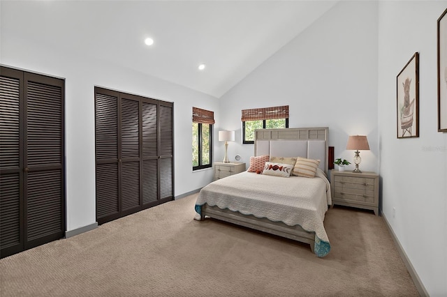 bedroom featuring carpet floors, multiple closets, high vaulted ceiling, and recessed lighting