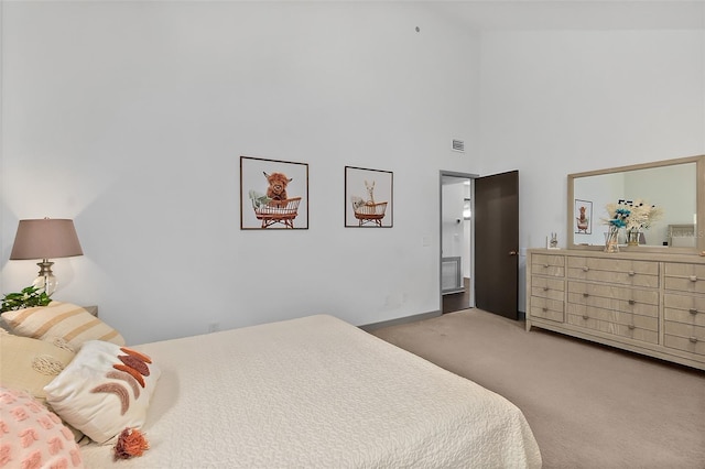 bedroom with visible vents, baseboards, carpet flooring, and a towering ceiling