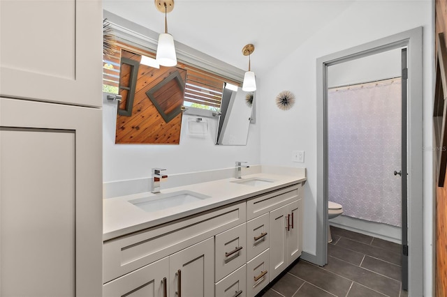 bathroom featuring tile patterned flooring, double vanity, a sink, and toilet