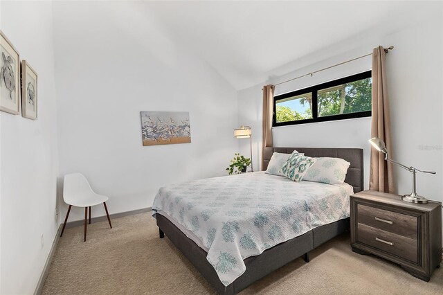 bedroom with light carpet, baseboards, and vaulted ceiling