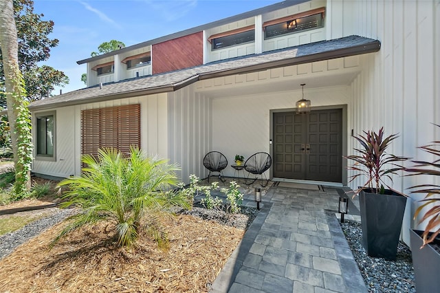 view of exterior entry with a shingled roof