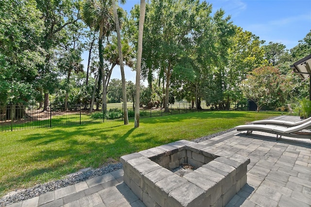 view of community with an outdoor fire pit, a patio, a yard, and fence