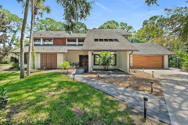 view of front of house featuring roof with shingles, a front lawn, a garage, and concrete driveway