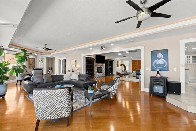 2924 River Point Dr, Daytona Beach, FL 32118 - living room featuring a tray ceiling, wood finished floors, ceiling fan, and a stone fireplace
