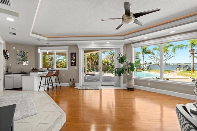 2924 River Point Dr, Daytona Beach, FL 32118 - living area featuring light wood-style flooring, a wealth of natural light, visible vents, a tray ceiling, and ceiling fan