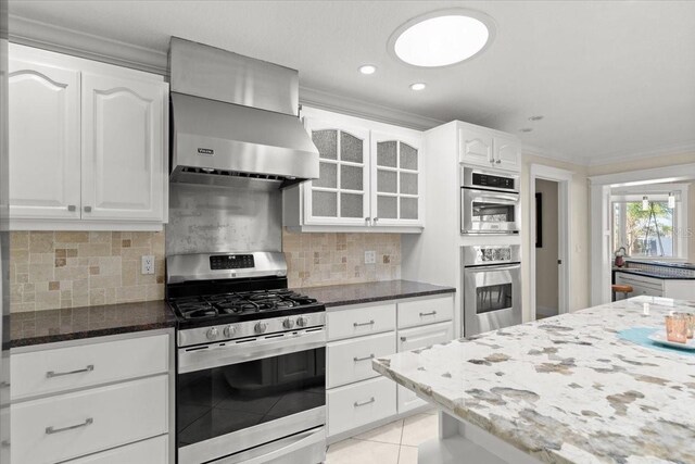 2924 River Point Dr, Daytona Beach, FL 32118 - kitchen featuring dark stone countertops, backsplash, light tile patterned flooring, wall chimney exhaust hood, and stainless steel appliances