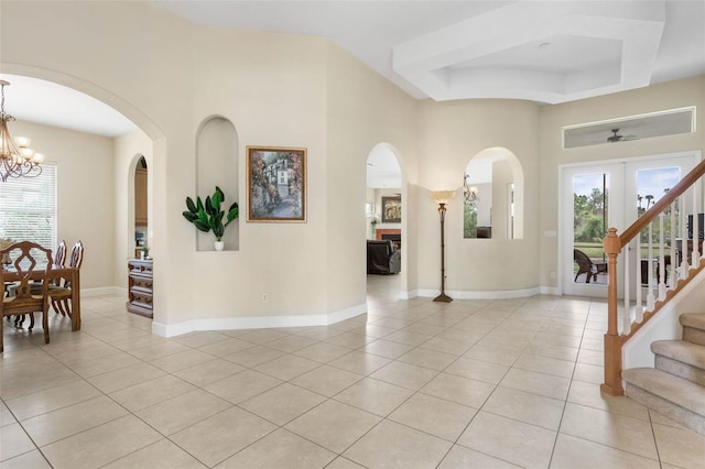 65 Heron Dr, Palm Coast, FL 32137 - foyer entrance with light tile patterned floors, a raised ceiling, arched walkways, and an inviting chandelier