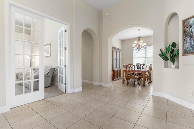 65 Heron Dr, Palm Coast, FL 32137 - interior space featuring arched walkways, light tile patterned floors, a notable chandelier, and french doors