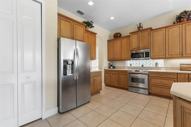 65 Heron Dr, Palm Coast, FL 32137 - kitchen with brown cabinets, light tile patterned floors, light countertops, and stainless steel appliances