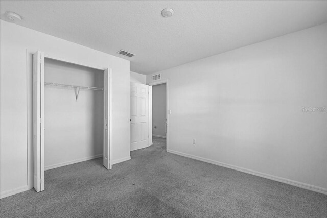 10 Post Oak Ln, Palm Coast, FL 32164 - unfurnished bedroom with carpet floors, a textured ceiling, baseboards, and a closet