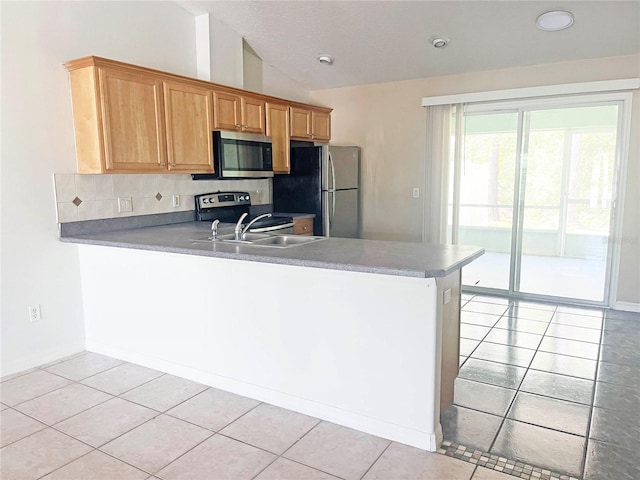 3 Frank Pl, Palm Coast, FL 32137 - kitchen featuring light tile patterned floors, a peninsula, vaulted ceiling, appliances with stainless steel finishes, and decorative backsplash