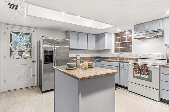 600 10th St, Daytona Beach, FL 32117 - kitchen with under cabinet range hood, stainless steel fridge, white electric stove, and gray cabinets