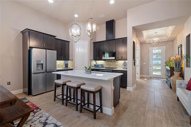 816 Creekwood Dr, Ormond Beach, FL 32174 - kitchen with dark brown cabinetry, stainless steel appliances, light countertops, a kitchen bar, and a notable chandelier