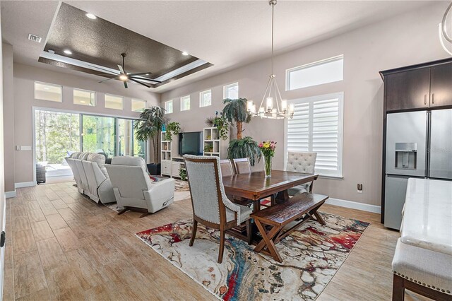 816 Creekwood Dr, Ormond Beach, FL 32174 - dining space featuring a tray ceiling, light wood finished floors, baseboards, and ceiling fan with notable chandelier