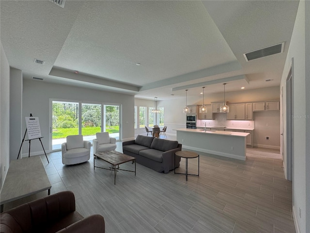 1665 Lake Reserve Dr, Deland, FL 32724 - living area featuring a tray ceiling, a textured ceiling, baseboards, a chandelier, and wood tiled floors