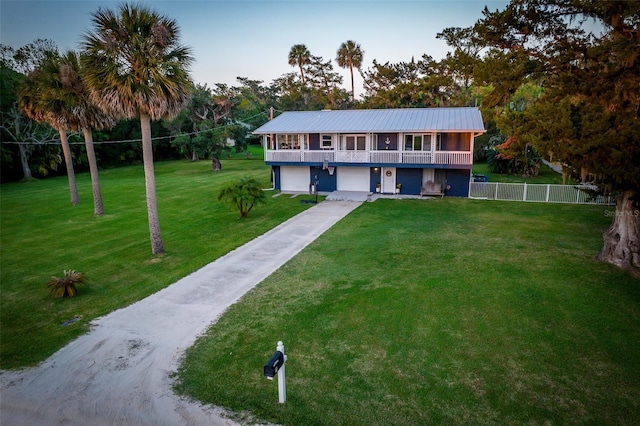 view of front facade featuring a front lawn, fence, an attached garage, and driveway