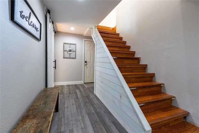 stairs with baseboards, recessed lighting, a barn door, and wood finished floors