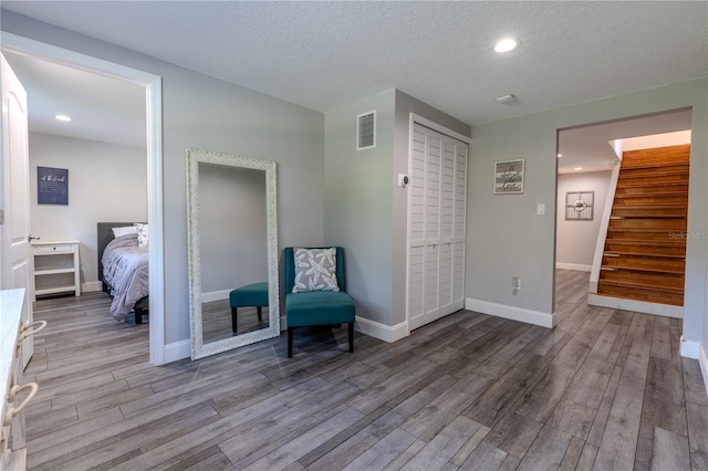 sitting room featuring wood finished floors, baseboards, visible vents, and stairway